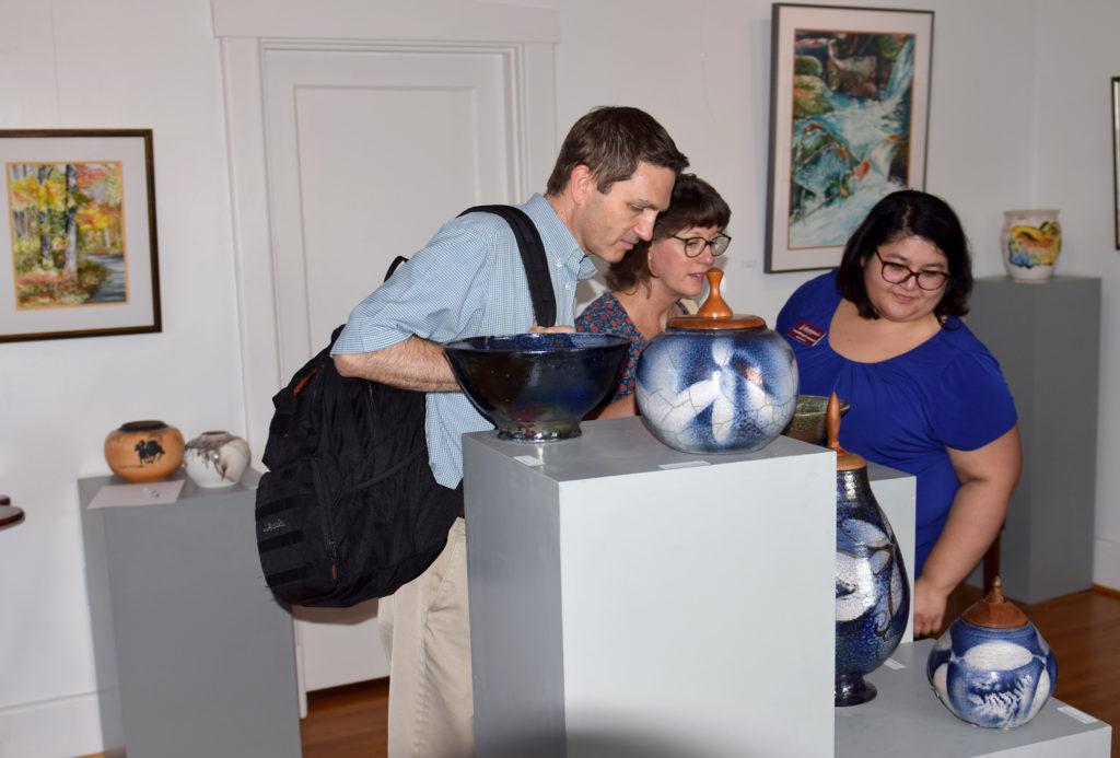 Susie Trejo Williams, left, assistant professor of art and design at Campbellsville, shows some of the Scott’s art to Vonnie and Stephen Skaggs at the reception honoring the Scott’s work. (Campbellsville University Photo by Luke Young)